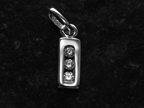 Ein silberner rhodiniert Anhänger in Form eines rechteckigen Blocks mit drei Zirkonia-Steinen, geschaffen vom Juwelier Harnisch, mit dem Buchstaben I.