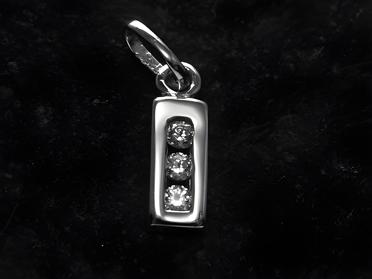 Ein silberner rhodiniert Anhänger in Form eines rechteckigen Blocks mit drei Zirkonia-Steinen, geschaffen vom Juwelier Harnisch, mit dem Buchstaben I.