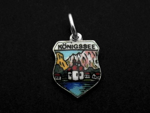 Ein silberner Anhänger in Form eines Wappens mit dem Schriftzug Königssee, farbenfrohen Bergmotiven und einer Darstellung des Königssees, hergestellt von Juwelier Harnisch, Bayern.