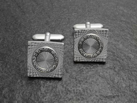 10065-0 Silberfarbene Manschettenknöpfe mit Strass Steinen in Weiß, Hersteller: Juwelier Harnisch, quadratische Form mit dekorativem Muster und runder Einlage umgeben von funkelnden Steinen.