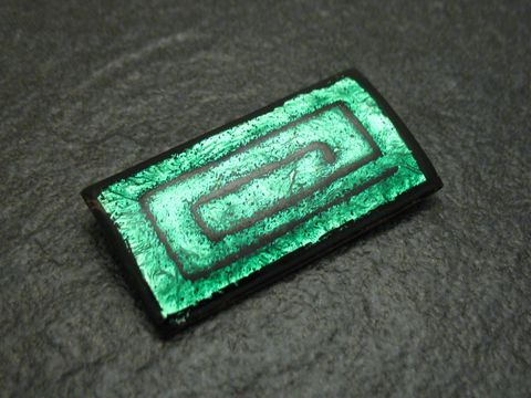 60899-0 Eine grün-schwarze Emaille Brosche in Spiralform, vergoldet, im Vintage-Stil vom Juwelier Harnisch, zeigt ein elegantes und raffiniertes Design mit glänzender Oberfläche.