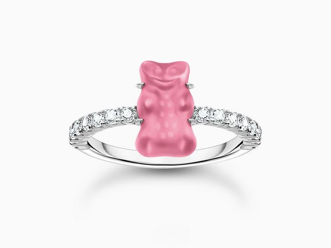 Der Thomas Sabo HARIBO Ring zeigt einen rosa-pinken Gummibärchen-Anhänger in der Mitte, umgeben von funkelnden Zirkonia-Steinen auf einem Silberband, elegant und verspielt.