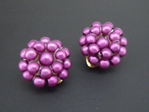 Ohrclip in lila Perlentraum mit goldfarbenem Element und seidenmatt synthetischer Zuchtperle, gefertigt vom Juwelier Harnisch, elegantes und auffälliges Schmuckstück.