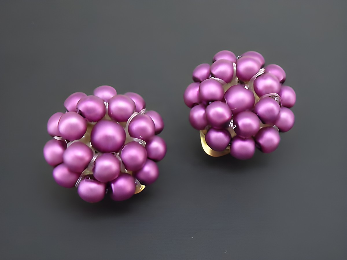 Ohrclip in lila Perlentraum mit goldfarbenem Element und seidenmatt synthetischer Zuchtperle, gefertigt vom Juwelier Harnisch, elegantes und auffälliges Schmuckstück.