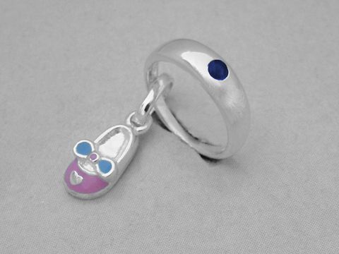 Silber Taufring mit rosa Schuh SAFIR, Hersteller Juwelier Harnisch, zeigt einen filigranen Anhänger in Form eines Babyschuhs mit blauem und rosa Design.