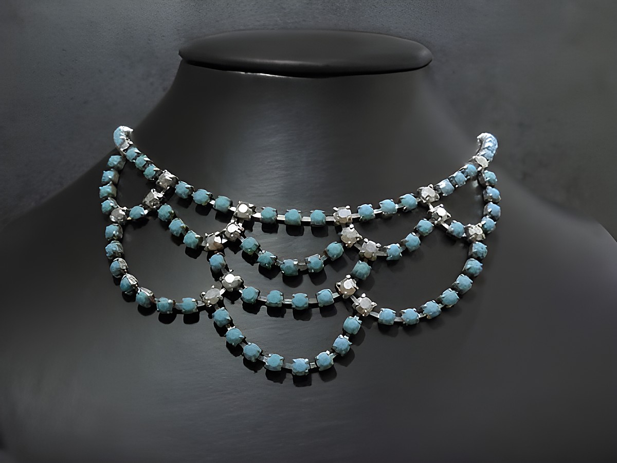 Auf dem Bild ist eine aufwendig gestaltete Strasskette in Türkis und silberfarben zu sehen. Die Kette hat eine Länge von 42 cm und eine silberfarbene Fassung, hergestellt von Juwelier Harnisch.