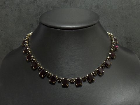 Strass Kette kultig in granatrot, 40-43 cm, goldfarben, von Juwelier Harnisch, mit goldfarbener Fassung, auf einem Schmuckständer präsentiert.