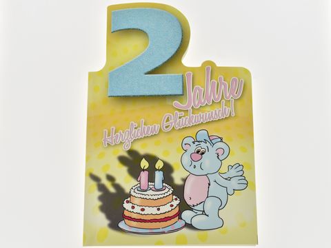 Geburtstagskarte mit einem niedlichen Bärchen, das vor einer Geburtstagstorte steht. Die Karte zeigt die Zahl zwei sowie den Text Herzlichen Glückwunsch. Hersteller Juwelier Harnisch.