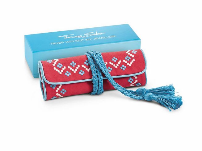 50440712-0 Schmuckrolle von Thomas Sabo in rot und türkis mit ethnischem Muster, geflochtenem Verschluss und Quasten, präsentiert in einer blauen Geschenkbox. Ideal zur Aufbewahrung von Schmuck.