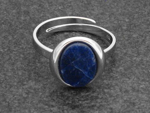 Silberring in ovaler Form, verstellbar, mit einem Sodalithstein, rhodiniert, Hersteller Juwelier Harnisch. Der Ring präsentiert sich elegant und modern auf einem dunklen Hintergrund.