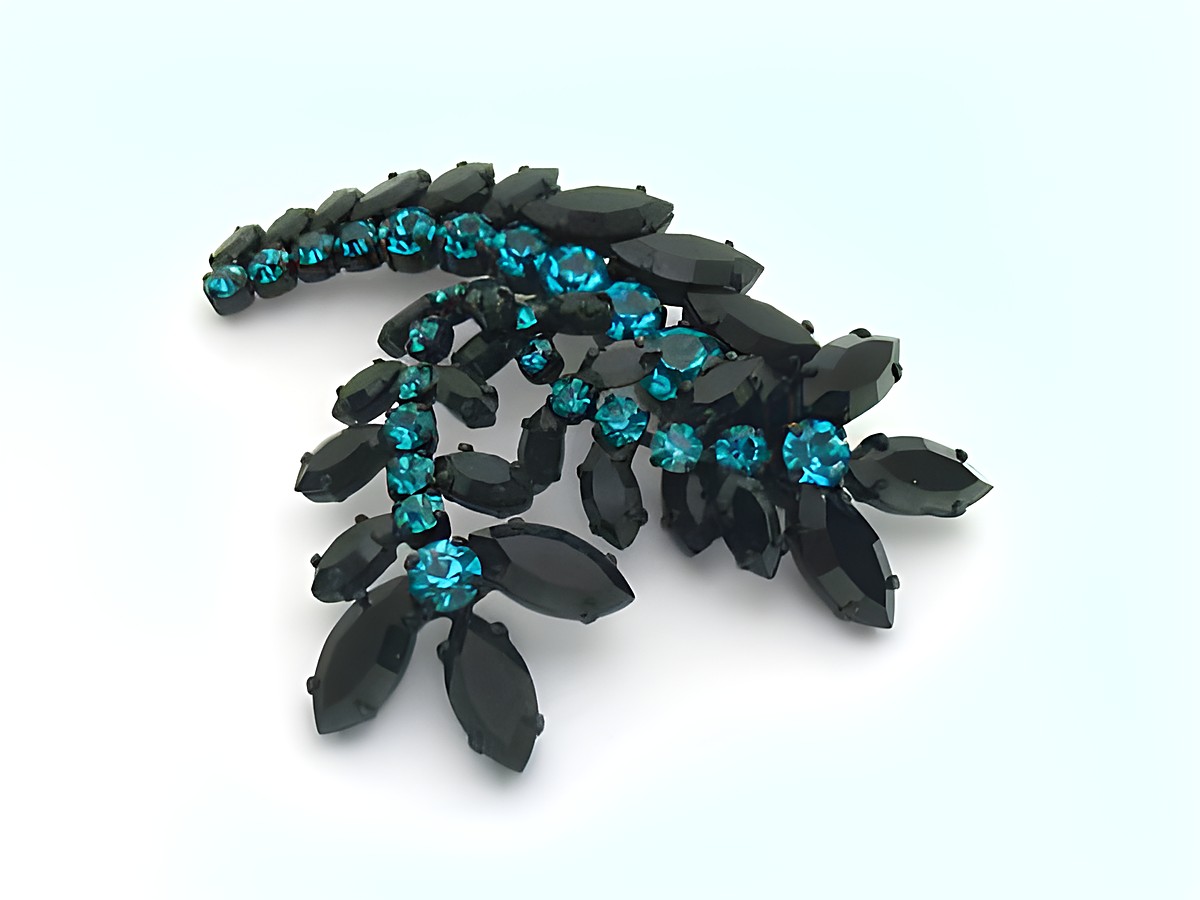 Strass Brosche in Türkis und Schwarz, blumenförmig gefasst, vom Hersteller Juwelier Harnisch, präsentiert sich elegant mit funkelnden Akzenten in längst gestellten schwarzen Steinen.