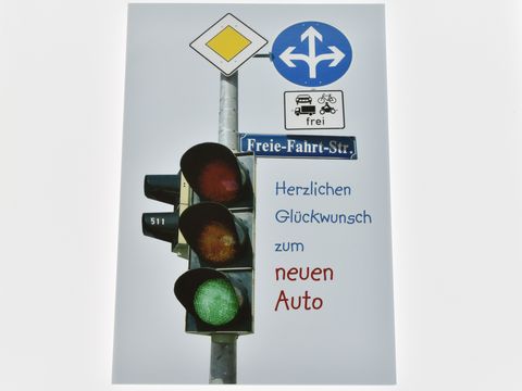 Eine Grußkarte mit einer grünen Ampel und Verkehrsschildern, versehen mit dem Text Herzlichen Glückwunsch zum neuen Auto, Hersteller Juwelier Harnisch.