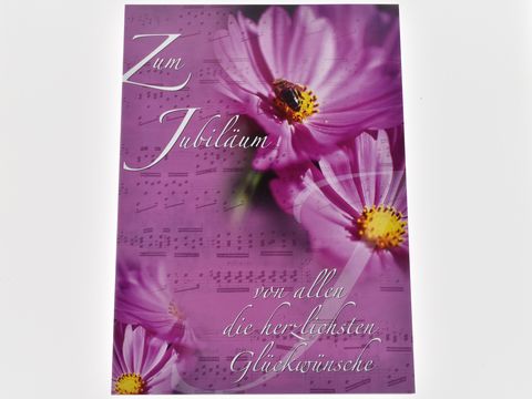 Glückwunschkarte mit einem Notenblatt-Hintergrund und einer floral gestalteten Vorderseite, die pinke Blumen zeigt, mit dem Text zum Jubiläum und den besten Glückwünschen. Hersteller Juwelier Harnisch.