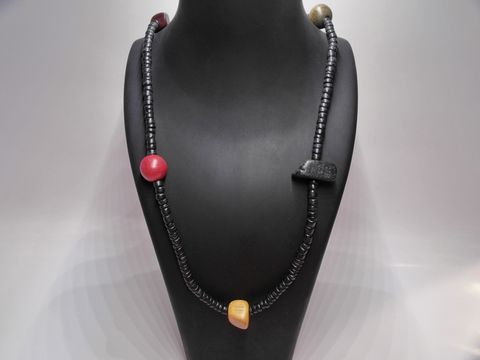 61900-0 Holzkette Multiform 25 mm bunt 90 cm Holz Schmuck von Juwelier Harnisch, zeigt eine farbenfrohe Kette mit verschiedenen Holzelementen auf einem schwarzem Schmuckständer.