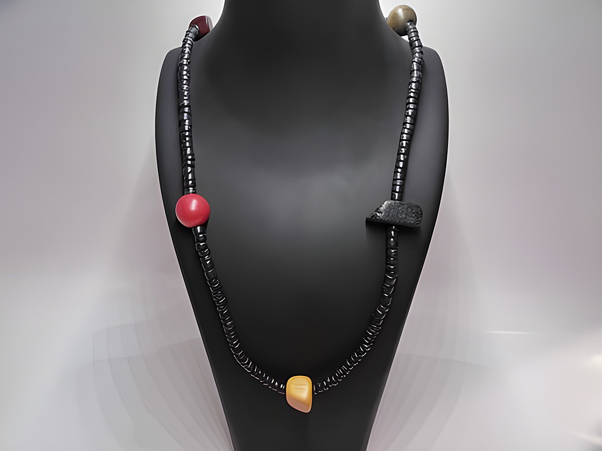 Holzkette Multiform 25 mm bunt 90 cm Holz Schmuck von Juwelier Harnisch, zeigt eine farbenfrohe Kette mit verschiedenen Holzelementen auf einem schwarzem Schmuckständer.