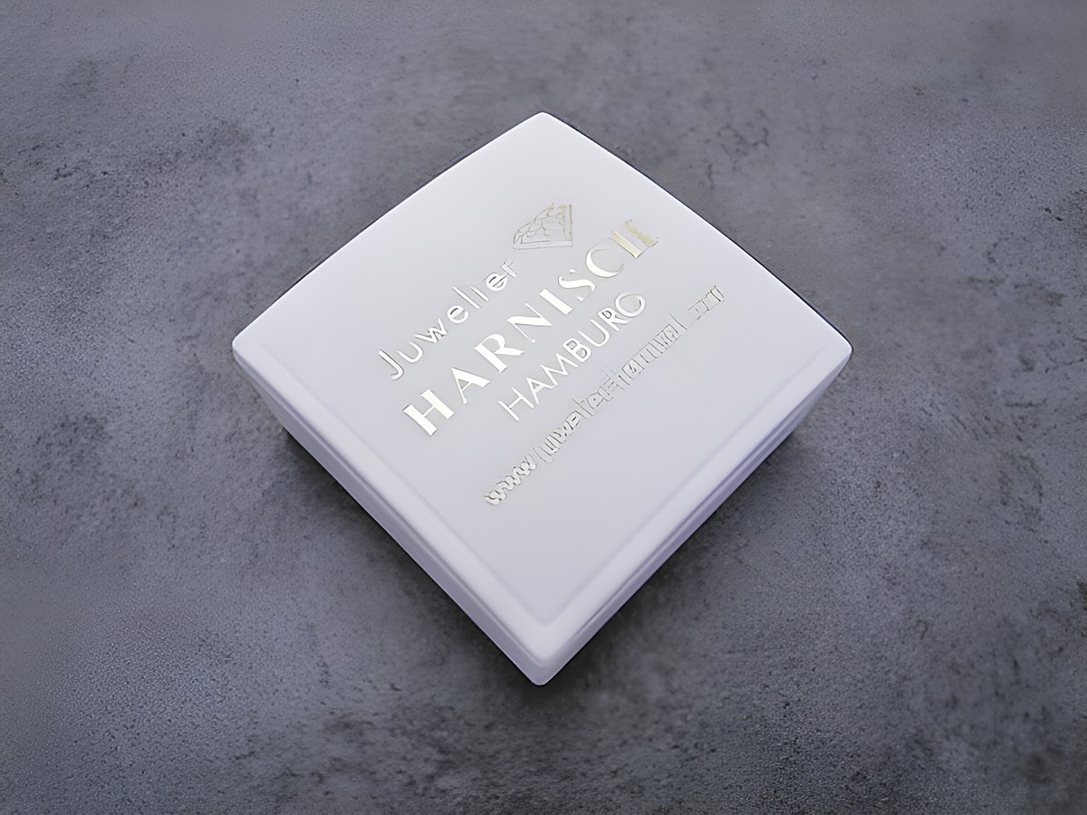 Geschenkschachtel 4 x 4 cm von Juwelier Harnisch in Weiß mit goldener Schrift und Firmenlogo, ideal für Schmuckpräsentationen und besondere Anlässe.