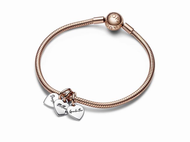 Armband aus Sterlingsilber mit roségoldvergoldeter Kette und drei gravierten Herz-Anhängern, die die Worte Tochter, Mutter und Großmutter tragen. Elegant und symbolisch für Familientraditionen.