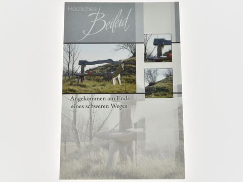 Trauerkarte mit der Aufschrift "Herzliches Beileid", umgeben von Bildern einer Bank in der Natur, erstellt von Juwelier Harnisch, Darstellung der Trauer und des Gedenkens.