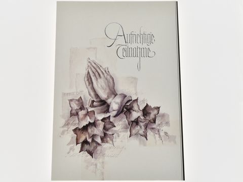 Auf der Trauerkarte sind betende Hände zu sehen, umringt von Efeublättern. Darüber steht in eleganter Schrift "Aufrichtige Anteilnahme". Hersteller ist Juwelier Harnisch.