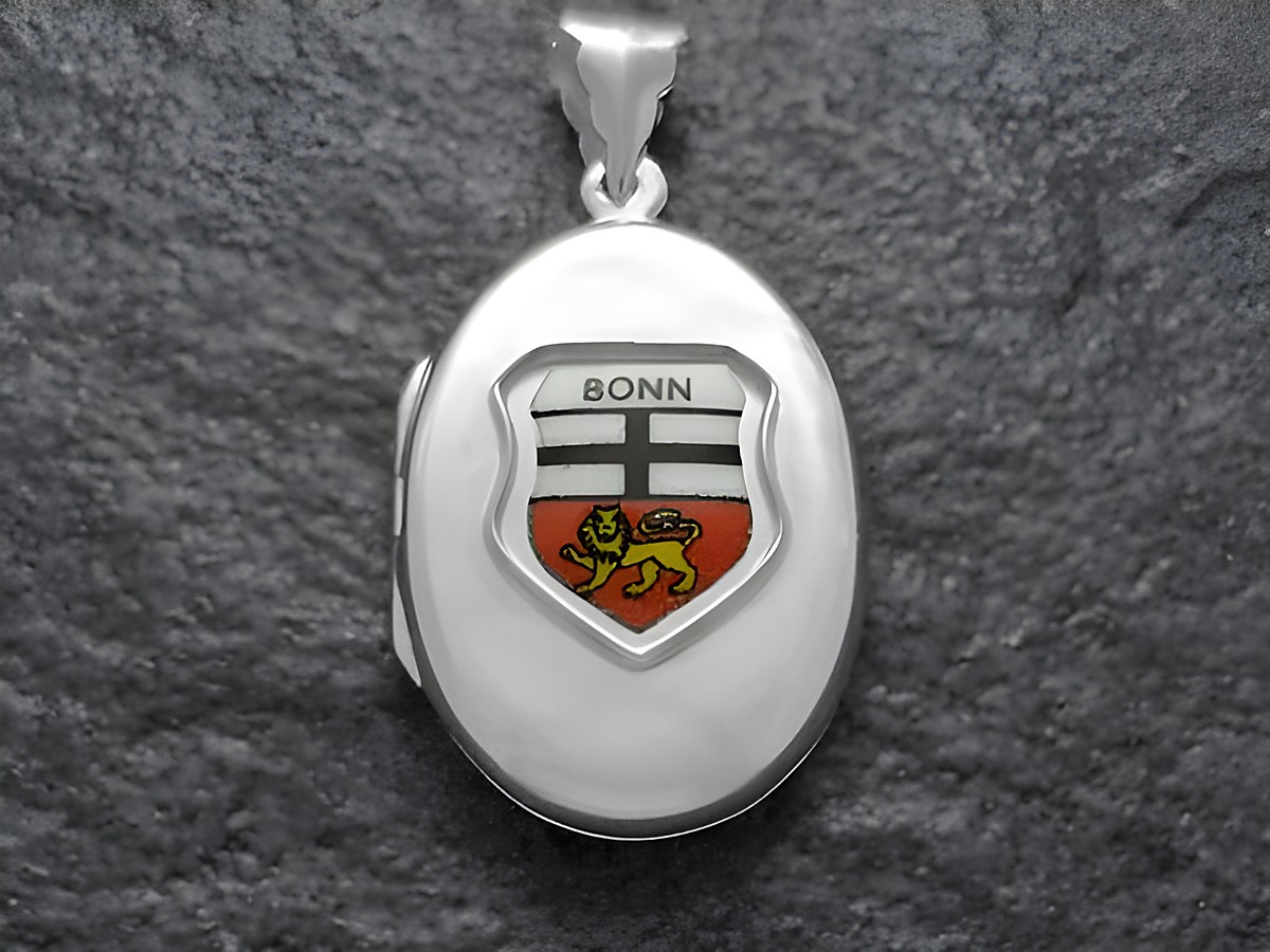Das Bild zeigt ein silbernes Medaillon mit dem Stadtwappen von Bonn. Das Wappen ist farblich gestaltet und zeigt einen goldenen Löwen auf rotem Hintergrund sowie die Schrift Bonn.
