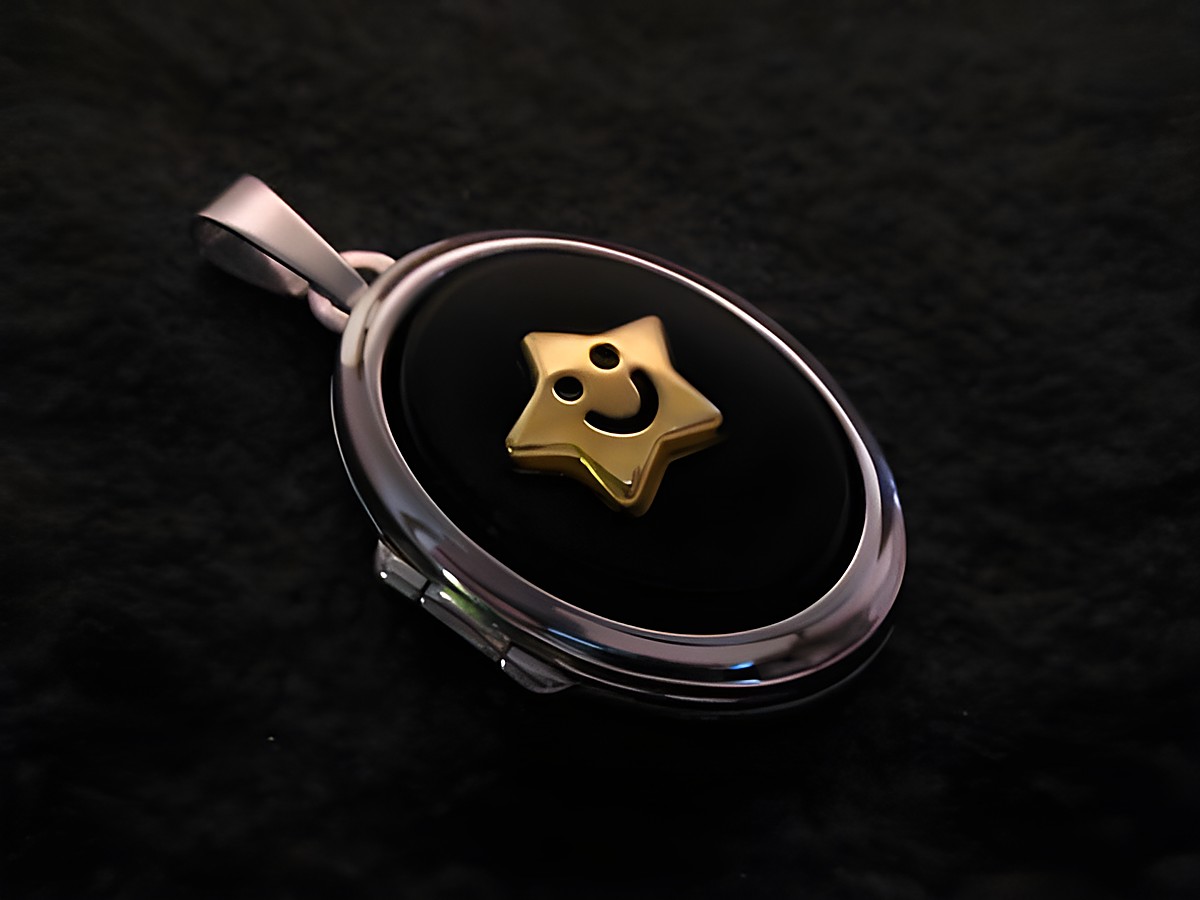 Medaillon aus Sterling Silber mit einem Cabochon aus Onyx in Schwarz und einem goldenen Stern mit lächelndem Gesicht des Herstellers Juwelier Harnisch.