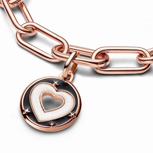 Ein eleganter Herzen Medaillon-Charm von Pandora ME in Roségold vergoldet mit synthetischem Perlmutt in Weiß, verziert mit Sternen und einem herzförmigen Ausschnitt.