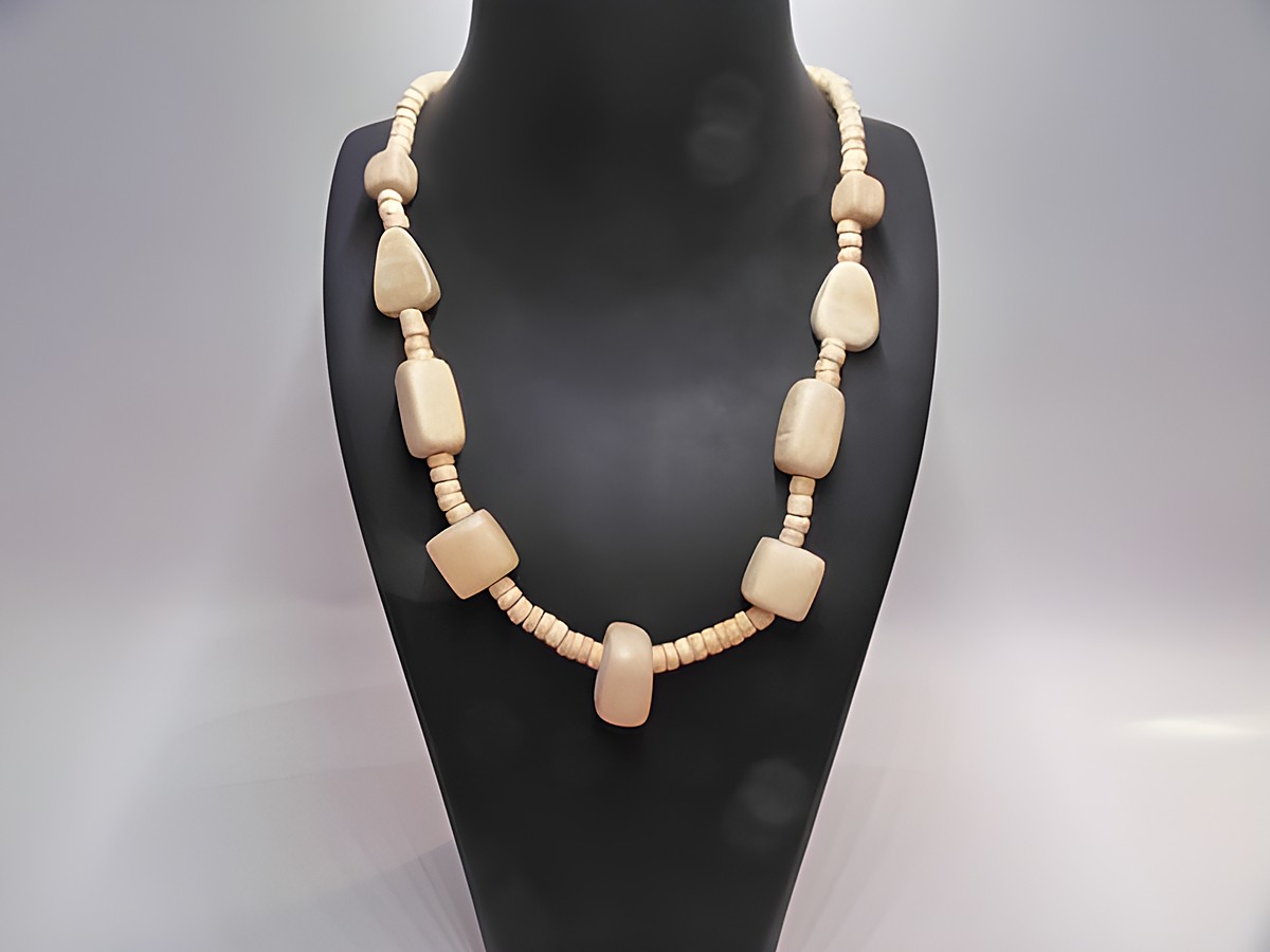 Holzkette aus naturbraunem Holz mit verschiedenen Formen, 20 mm dick und 60 cm lang, präsentiert auf einem dunklen Schmuckständer, Hersteller Juwelier Harnisch.
