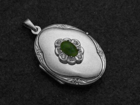 Jadegrüner Medaillon Cabochon aus Sterling Silber rhodiniert, von Juwelier Harnisch, geschmückt mit einem ovalen grünen Stein und einem floralen Design.