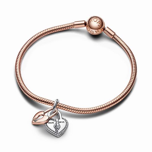Bicolor drehbarer Herz-Schloss Doppelter Charm-Anhänger von Pandora in Roségold vergoldet mit klaren Zirkonia auf einem eleganten Armband, ideal für Valentinstag.