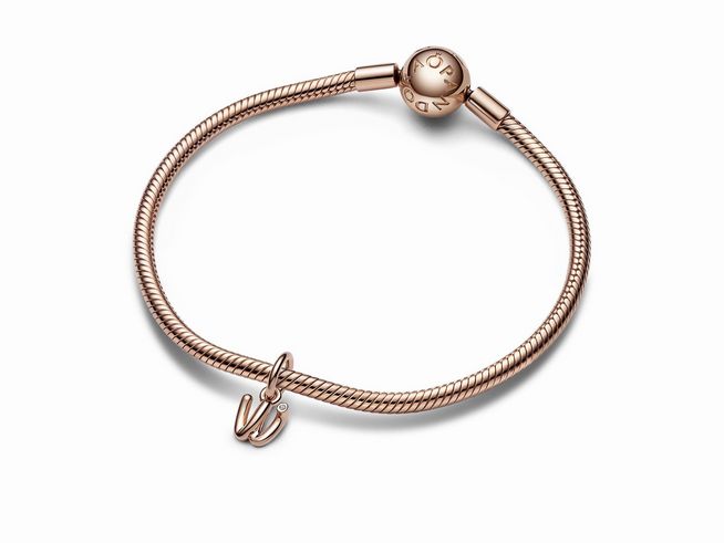 Ein elegantes Pandora Charm mit dem Buchstaben W aus roségold vergoldetem Material, verziert mit Zirkonia, auf einem geflochtenen Armband. Hersteller ist Pandora ROSE.