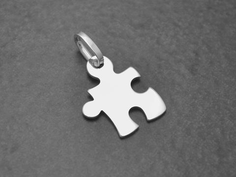 39519-0 Puzzle Teil aus Sterling Silber Anhänger von Juwelier Harnisch, Partner, auf grauem Hintergrund. Der Anhänger zeigt eine glatte, stilisierte Puzzlestück-Form.