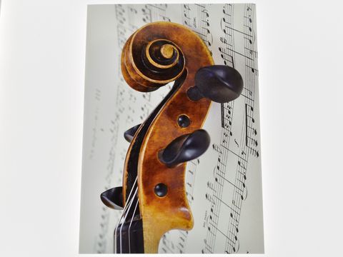 Eine Grußkarte mit dem Hals einer Violine im Vordergrund, vor einem Notenblatt. Hersteller: Juwelier Harnisch. Die Karte vermittelt musikalische Eleganz und Kunstfertigkeit.