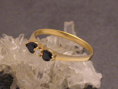Goldring entzückend mit zwei tiefblauen Saphiren und einem Zirkonia, Größe 56, Hersteller Juwelier Harnisch, bis Größe 56/18, auf Kristallbasis präsentiert.