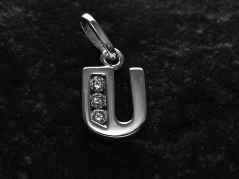 Anhänger in Form des Buchstabens U aus rhodiniertem Silber mit drei Zirkonia-Steinen, hergestellt von Juwelier Harnisch, glänzende Oberfläche und modernes Design.