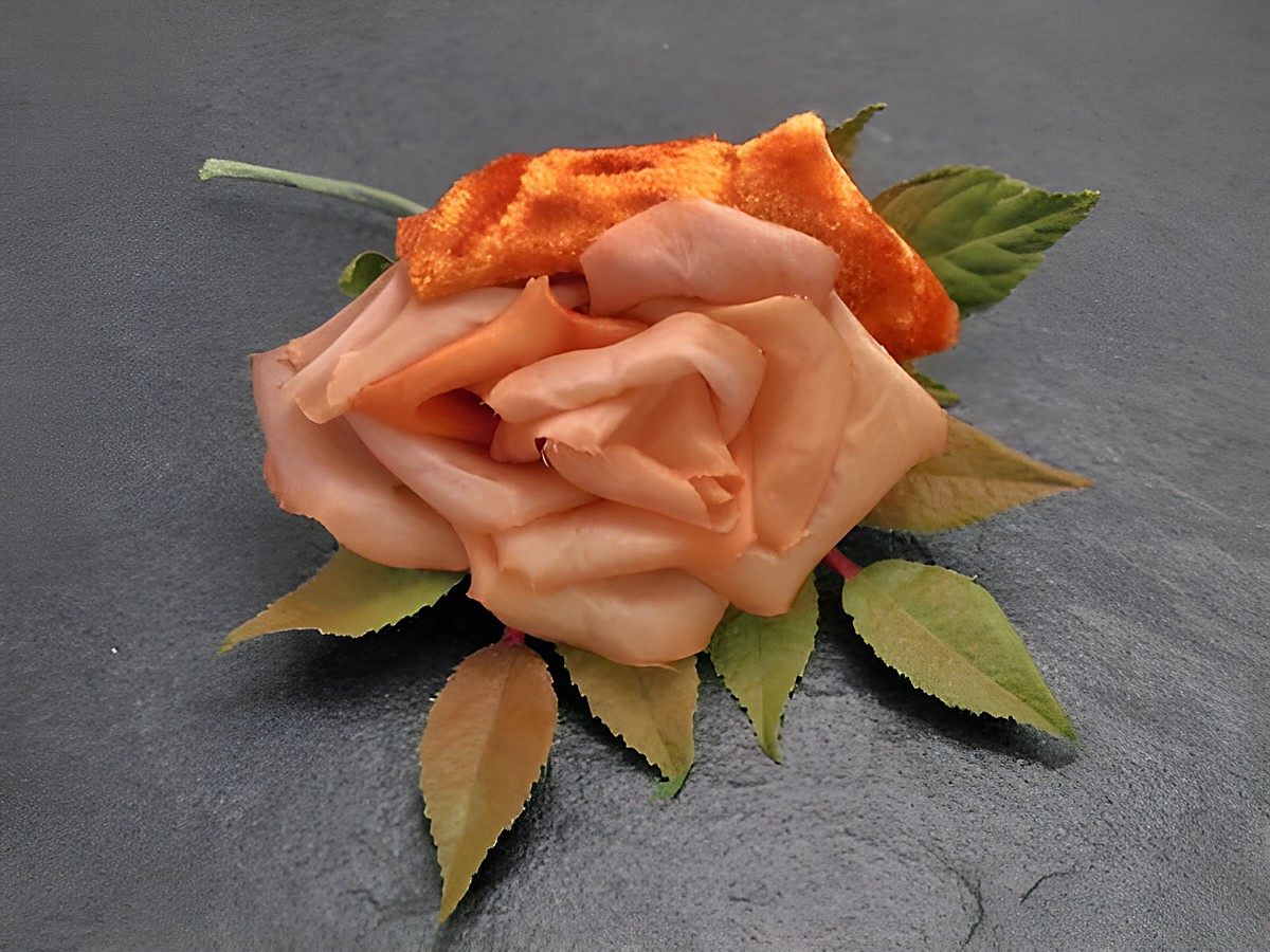 Verspielter Haarschmuck in Form einer orangefarbenen Blume aus Samt-Mix mit grünen Blättern, ideal für besondere Anlässe, Hersteller Juwelier Harnisch.