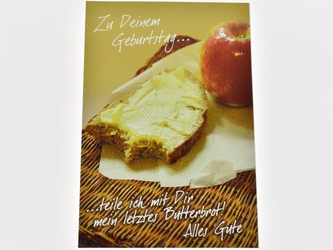 Eine Geburtstagskarte zeigt ein Butterbrot mit Butter und einen roten Apfel auf einem Tisch. Hersteller ist Juwelier Harnisch. Der Text auf der Karte wünscht alles Gute zum Geburtstag.