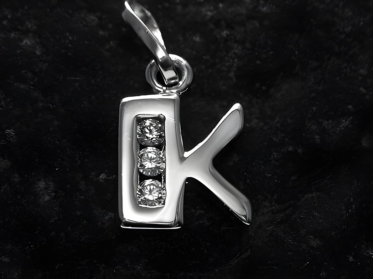 Anhänger aus Silber mit rhodiniertem Finish in Form des Buchstabens K, verziert mit drei Zirkonia-Steinen, hergestellt von Juwelier Harnisch.