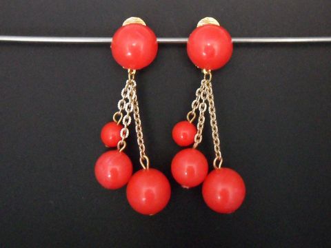 Ohrclips in rot mit zeitlosem Design aus Kunstharz und goldfarbenen Details, hergestellt von Juwelier Harnisch, elegant und auffällig.