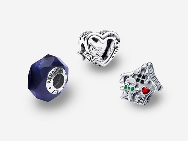 Drei Pandora Schmuckstücke in Sterling Silber und Zirkonia sind abgebildet, darunter eine herzförmige Perle mit Schriftzug und ein detailliertes Hausdesign, ergänzt durch eine facettierte lila Perle.