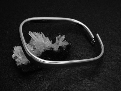 Armreifen rechteckig 7,1 mm aus echtem Silber rhodiniert mit einer Länge von 21 cm, Hersteller Juwelier Harnisch, auf einem natürlichen Untergrund aus Kristallen präsentiert.