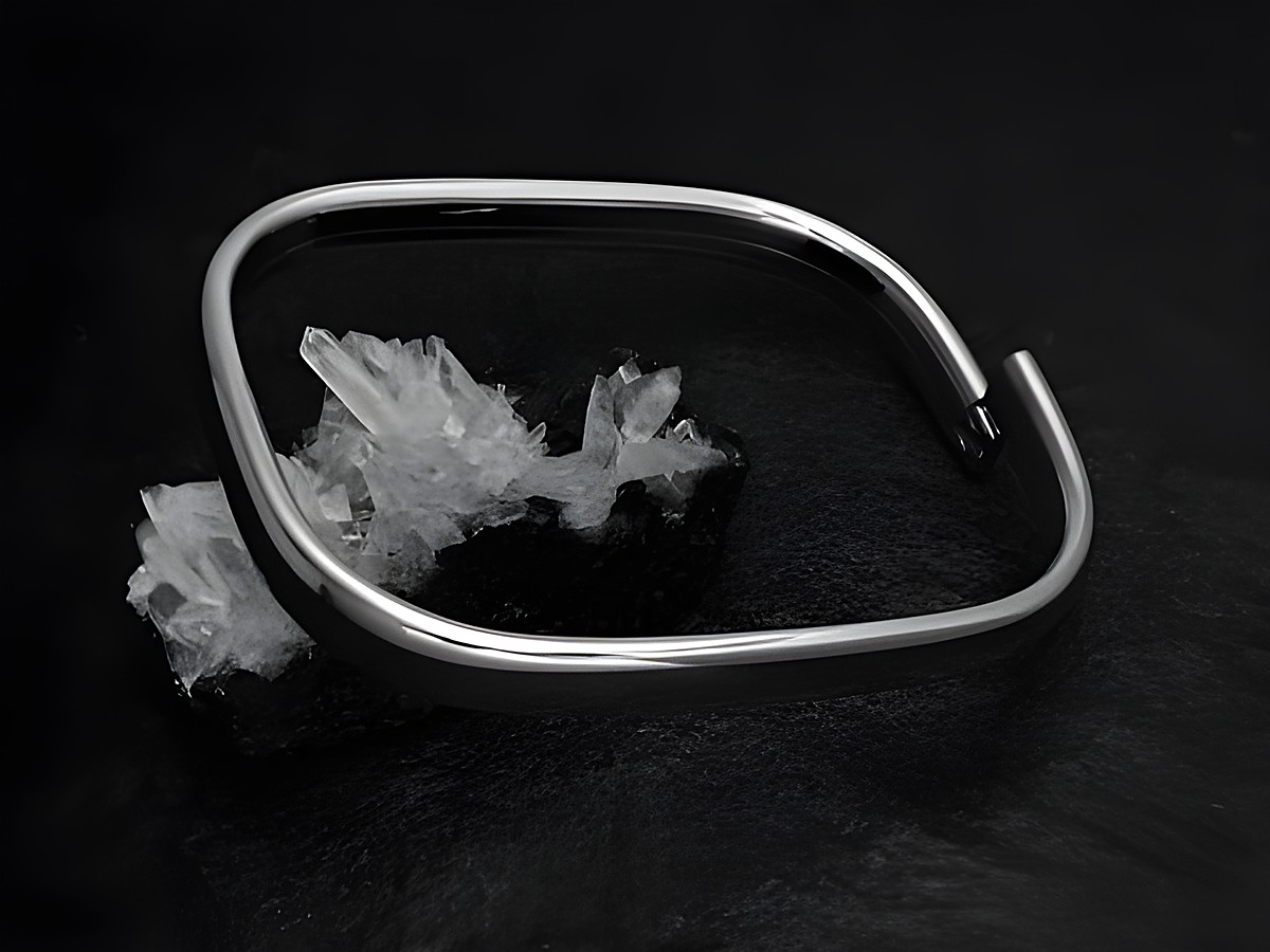 Armreifen rechteckig 7,1 mm aus echtem Silber rhodiniert mit einer Länge von 21 cm, Hersteller Juwelier Harnisch, auf einem natürlichen Untergrund aus Kristallen präsentiert.