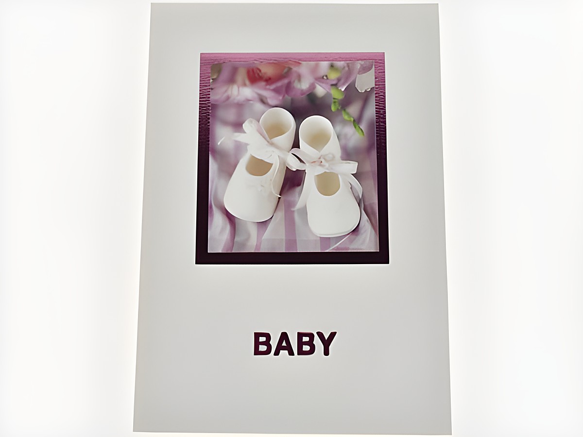 Glückwunschkarte mit Babyschuhen in Weiß und rosa Schleife, umgeben von Blumen, auf einem karierten Hintergrund, Hersteller Juwelier Harnisch.