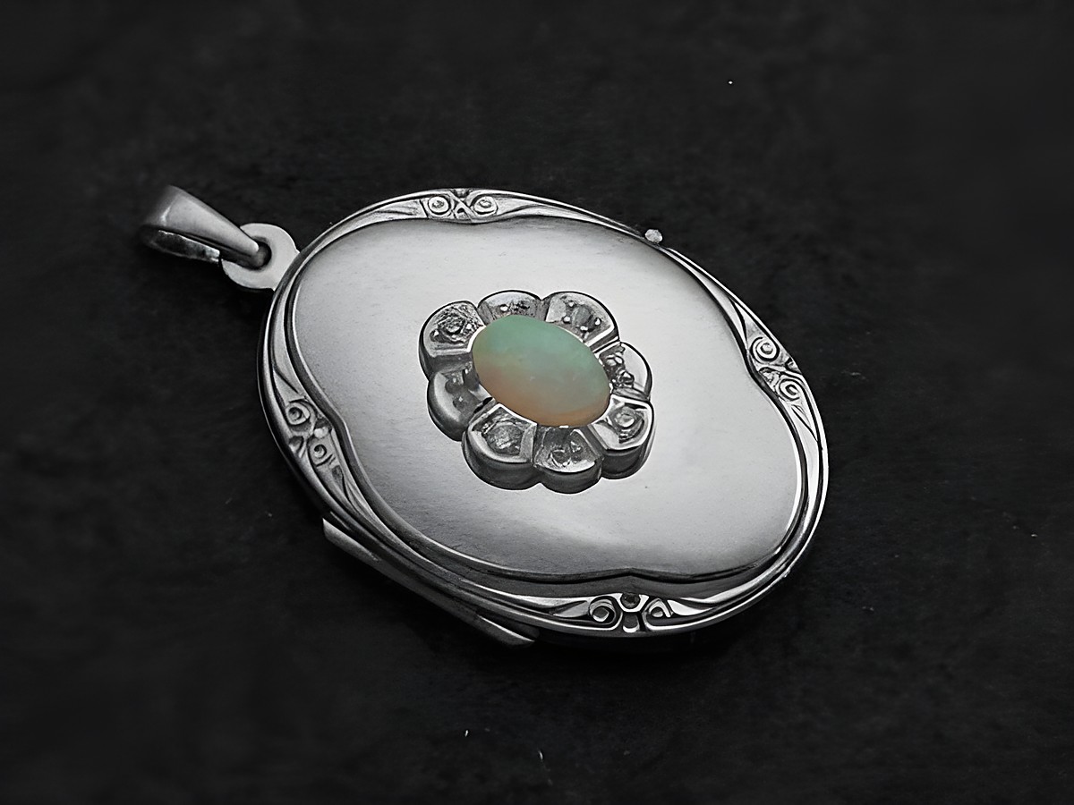 Medaillon aus Weißgold 333 mit einem weißen Opal Cabochon in der Mitte, umgeben von Brillanten, hergestellt von Juwelier Harnisch, filigrane Verzierung.