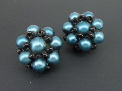 Ohrclip in blaugrün-schwarz mit blumigem Design, verziert mit goldfarbenen synthetischen Zuchtperlen, Hersteller Juwelier Harnisch, elegantes Schmuckstück für jeden Anlass.