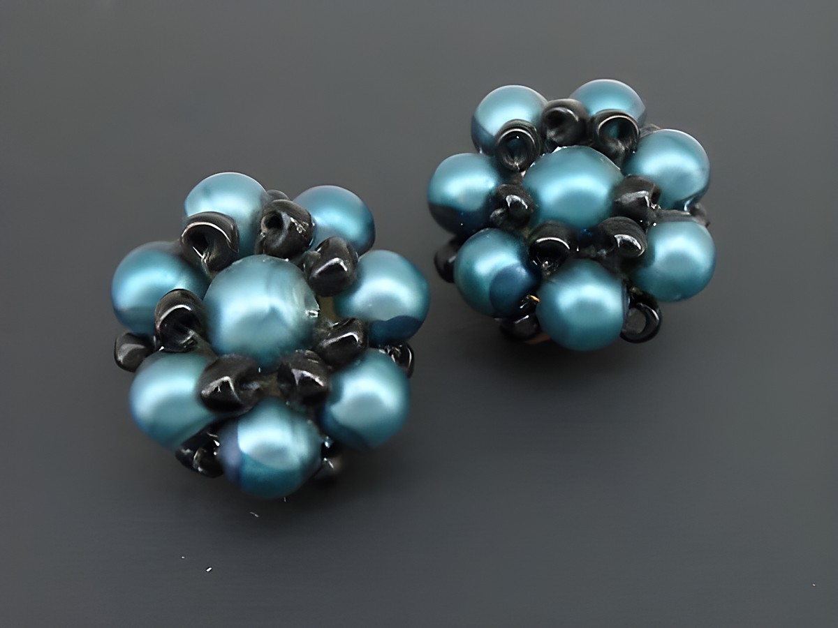 Ohrclip in blaugrün-schwarz mit blumigem Design, verziert mit goldfarbenen synthetischen Zuchtperlen, Hersteller Juwelier Harnisch, elegantes Schmuckstück für jeden Anlass.