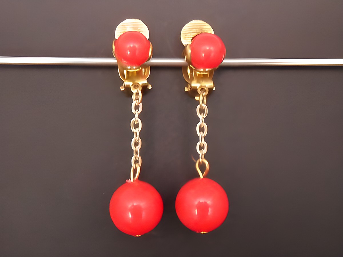 Ohrclip in zeitlosem Design mit hellroten Kunstharzkugeln und goldfarbenen Details, Hersteller Juwelier Harnisch, ideal für elegante Anlässe.