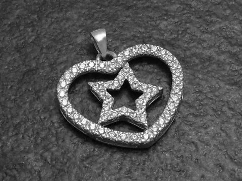 Ein Anhänger in Form eines Herzens mit einem innenliegenden Stern, hergestellt aus rhodiniertem Sterling Silber und besetzt mit Zirkonia, von Juwelier Harnisch, inspiriert von Sonne, Mond und Sternen.