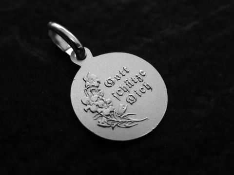 Ein Anhänger in Form einer runden Medaille aus Sterling Silber mit der Gravur Gott beschütze Dich und floralen Motiven, hergestellt von Juwelier Harnisch, Engel Raphael Schutzengel.