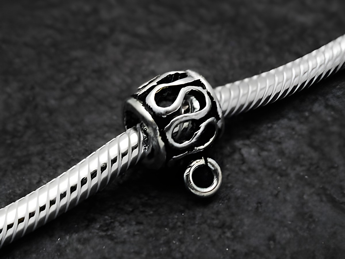 Schlaufen BLANKO charms Einhänger aus Sterling Silber mit einer Größe von 7 mm, gefertigt vom Juwelier Harnisch, auf einem geflochtenen Schmuckband abgebildet.